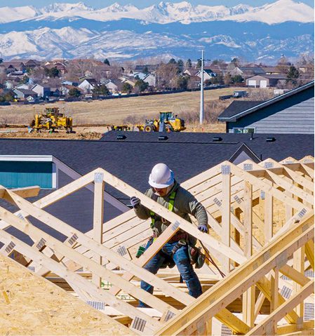 Construction worker building roof of home.