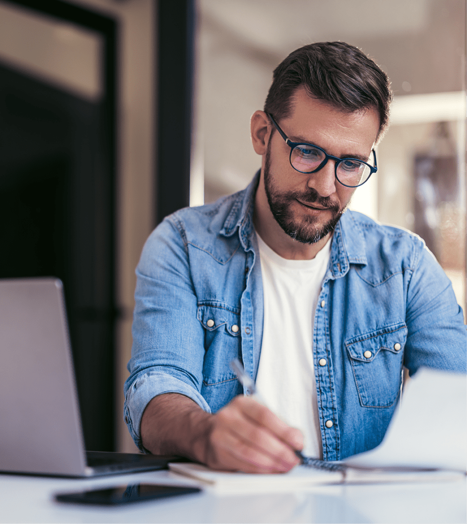 man writing on paper at a desk